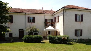 Un bâtiment à deux étages, doté d’un toit en tuiles, d’un patio couvert et d’une pelouse bien entretenue.
