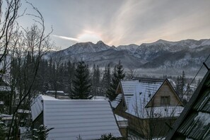 Un paysage de montagne enneigé avec une maison au premier plan.