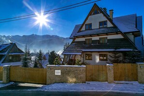 A chalet-style building with a sloped roof, wooden exterior, and a stone wall entrance.