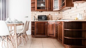 Una cocina con armarios de madera, horno empotrado y comedor con mesa y sillas.