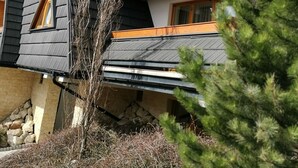 Un edificio de varios pisos con un diseño arquitectónico moderno, que presenta vigas de madera a la vista y una combinación de revestimiento oscuro y claro.