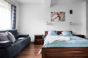 Une chambre à coucher avec un lit, un canapé, une table de chevet et un tableau au mur.