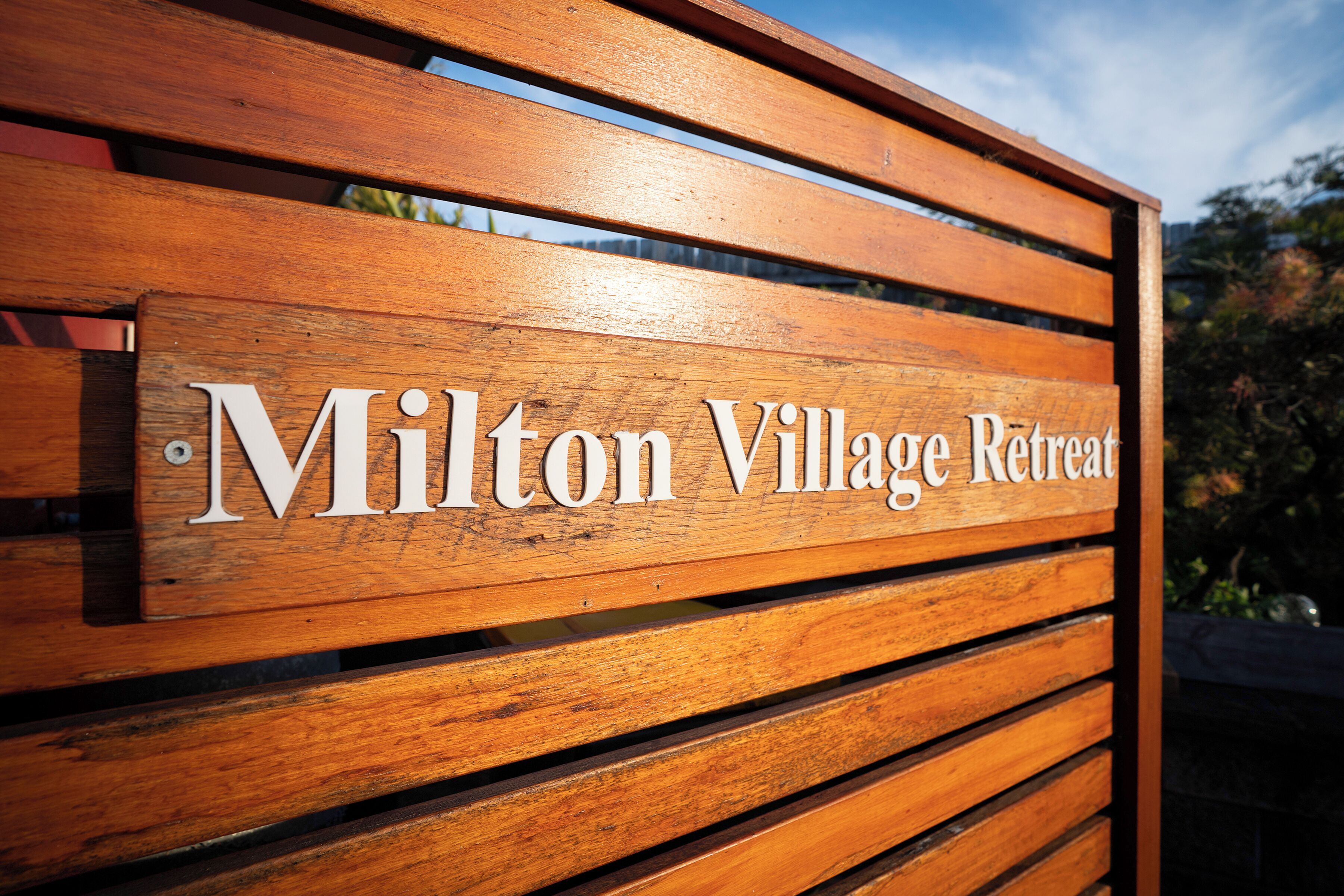 A wooden sign with the text "Milton Village Retreat".