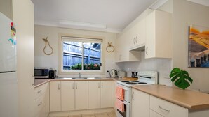 Una cucina con mobili bianchi, un fornello e un forno a microonde.