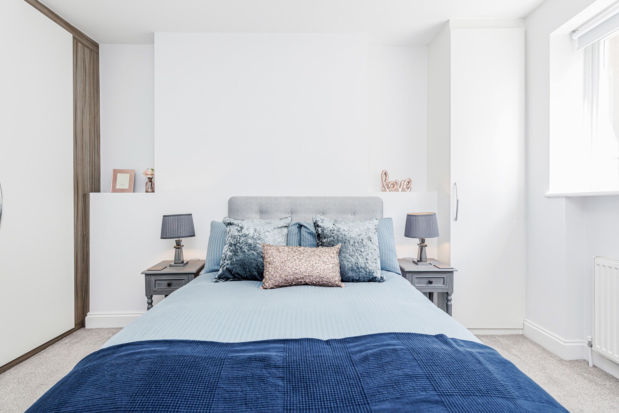 Een slaapkamer met een bed, twee nachtkastjes en een raam.