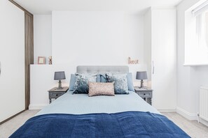 A bedroom with a bed, two bedside tables, and a window.