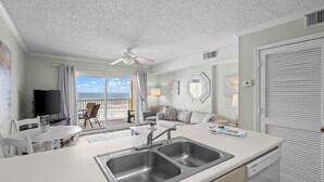 Eine moderne Küche mit einer doppelten Spüle, Essbereich und einem Balkon mit Meerblick.
