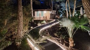 Una cabaña apartada rodeada de árboles, con un camino pavimentado que la lleva a ella.