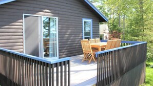 A wooden cabin with a deck, a dining table, and chairs. - Waterfront Cabin with Inground Pool, Dock, Tennis (Boothbay Harbor)