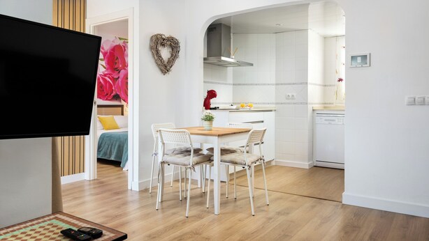 A modern apartment with a dining area, kitchen, and a TV in the living room. - Orquidea Apartment - Historical Center (Málaga)