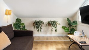 A modern living room with a brown sofa, a coffee table with a ship model, and two wall-mounted plant shelves. - Orquidea Apartment - Historical Center (Málaga)