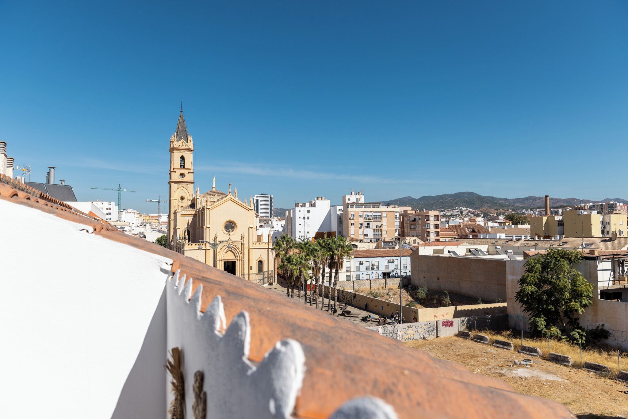A cityscape with a prominent church tower, a mix of residential and commercial buildings, and a clear blue sky.