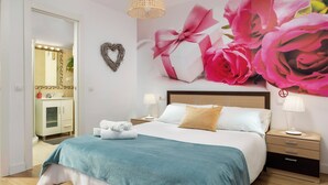 A bedroom with a large bed, a nightstand with a lamp, a dresser, and a mirror with lights. - Orquidea Apartment - Historical Center (Málaga)