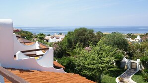 Ein Küstenwohngebiet mit terrakottafarbenen Dächern, üppigem Grün und Blick auf das Meer.