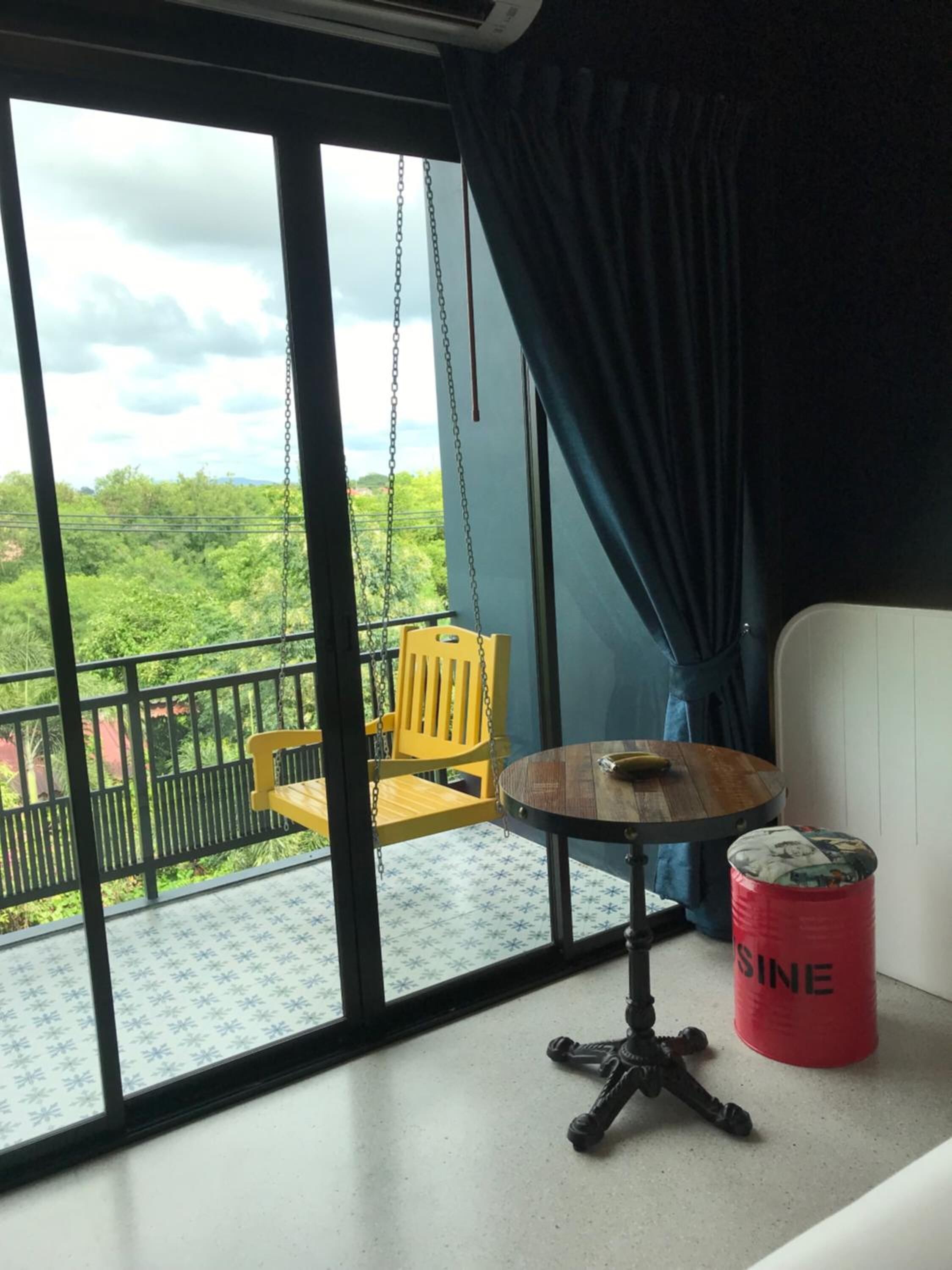 A balcony with a yellow chair, a small round table, and a red barrel labeled "SINE".