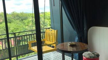 A balcony with a yellow chair, a small round table, and a red barrel labeled "SINE".