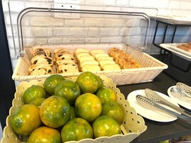 Un bufé con diversos alimentos, incluyendo pan, pasteles y frutas cítricas.