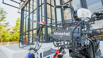 Una patineta eléctrica estacionada con una canasta delantera y una etiqueta que dice 'Mosstel Hotel'.