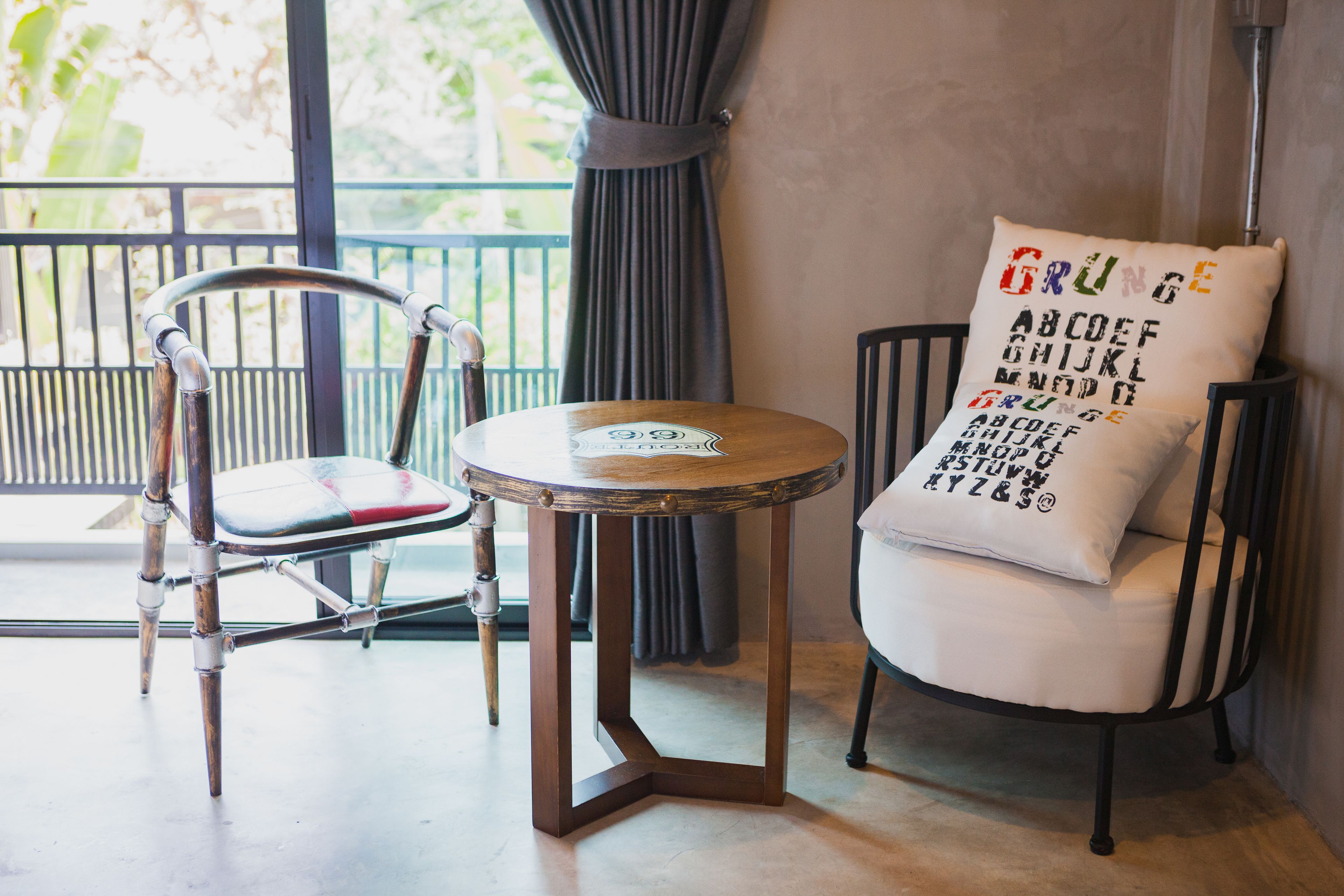 Una habitación moderna con una mesa redonda, una silla con cojín y una almohada decorativa con letras del alfabeto.