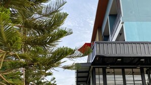 A modern building with a glass facade, outdoor sculptures, and a well-maintained grassy area. - Mosstel (Phitsanulok)