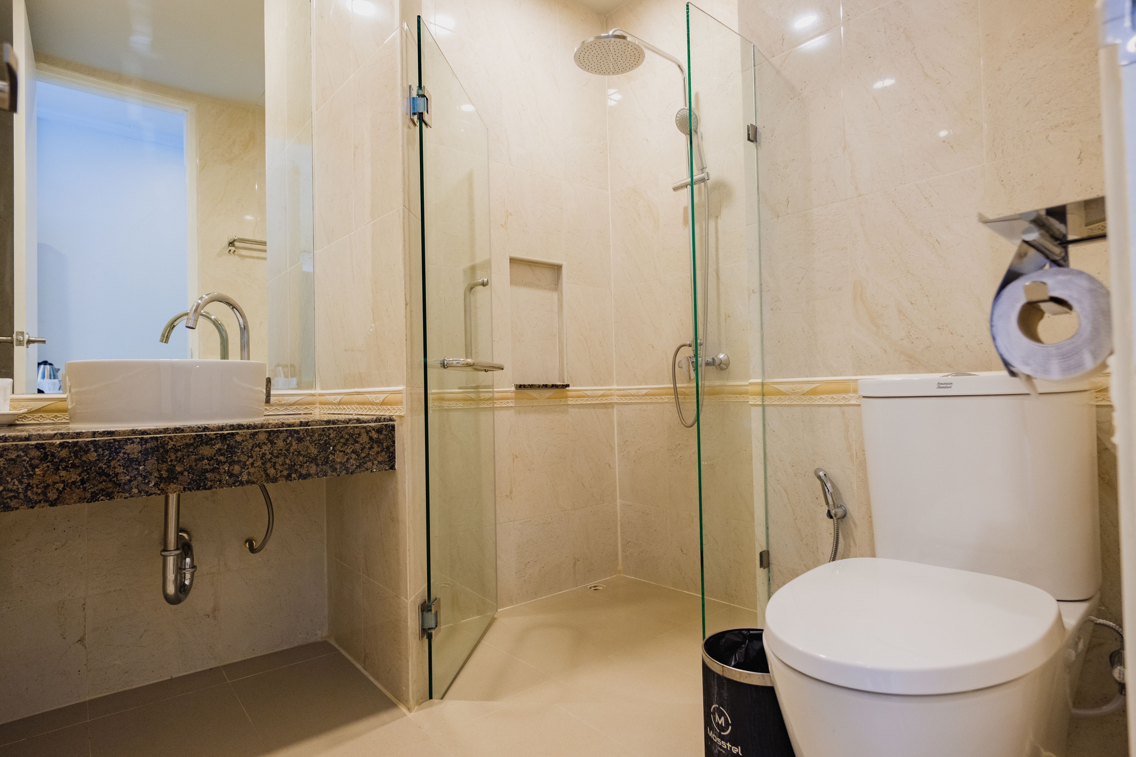 A modern bathroom with a glass-enclosed shower, a sink with a marble countertop, and a toilet.