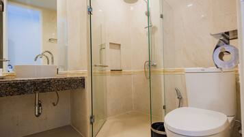 A modern bathroom with a glass-enclosed shower, a sink with a marble countertop, and a toilet.