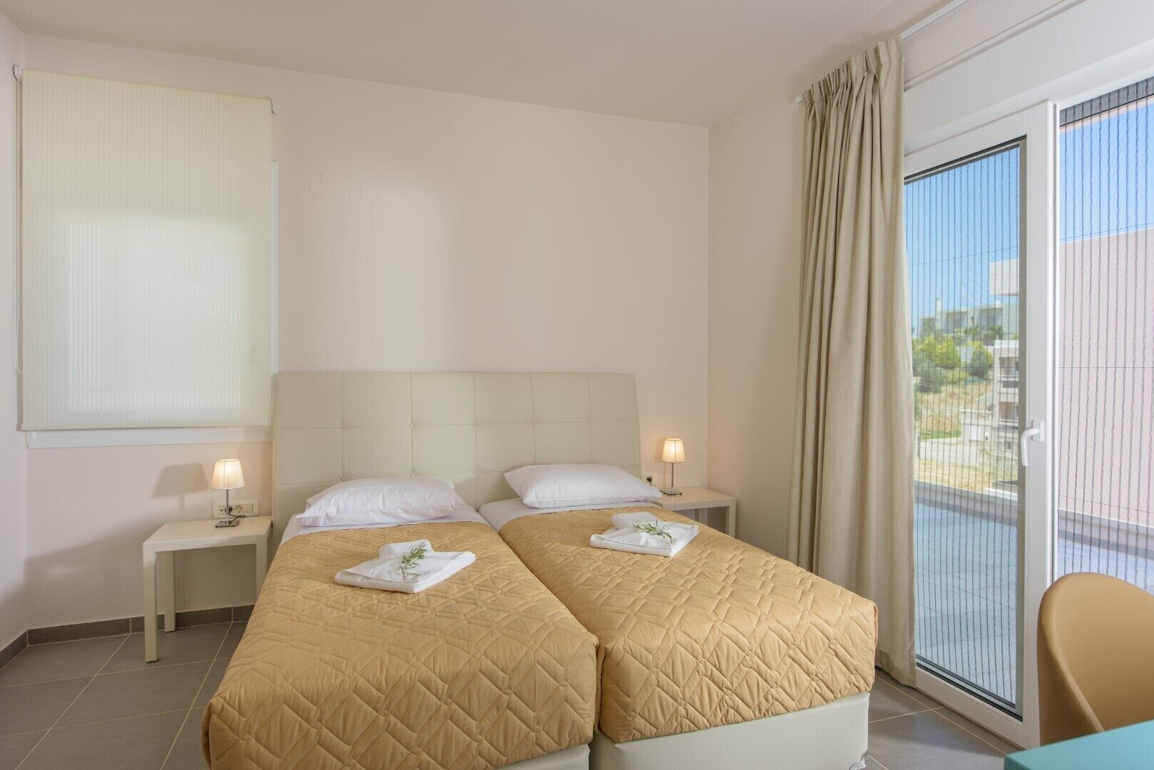 Een hotelkamer met twee bedden, een groot raam met gordijnen en uitzicht op de omgeving.