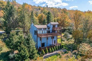 A multi-story building with balconies, surrounded by dense forest and autumn foliage. - Sky Ridge - Stunning Mountain Top Views, Hot Tub (Davis)