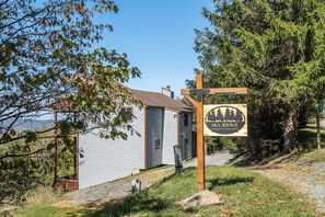 A small cabin with a wooden sign indicating 'Sky Ridge' and a view of a forested area. - Sky Ridge - Stunning Mountain Top Views, Hot Tub (Davis)