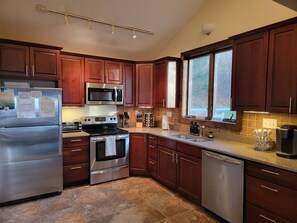 A modern kitchen with stainless steel appliances, wooden cabinets, and a large window providing natural light. - Sky Ridge - Stunning Mountain Top Views, Hot Tub (Davis)