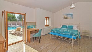 Une chambre à coucher avec un lit, un bureau, une chaise, une petite table et une fenêtre.