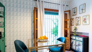 Un comedor con una mesa, sillas, un frutero y un mueble con obras de arte.