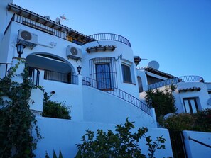 Stylish building with rounded balconies and arched windows, featuring lush greenery and multiple levels.