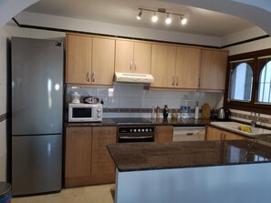 Enjoy cooking in this well-equipped kitchen with a refrigerator, microwave, oven, and stovetop, plus a large island and window with city views.