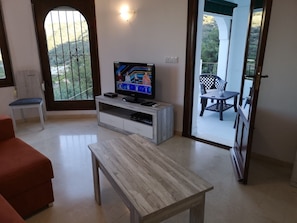 Relax in a peaceful space with a flat-screen TV, comfortable sofa, and sliding glass door to an outdoor seating area.