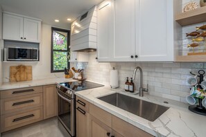 A modern kitchen with white cabinets, a stainless steel sink, and a built-in oven.