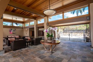 A spacious indoor area with a high ceiling, large windows, and a central round table with a potted plant. - Wailea Elua #102 Beautifully Remodeled Ocean View short walk to beach, shops! (Wailea)