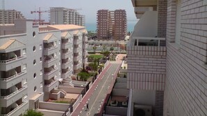 A multi-story residential building with balconies, a street in the foreground, and other buildings in the background. - Perfect views and location (Oropesa)