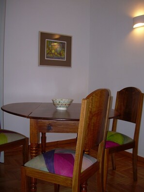 A dining table with a bowl, two chairs, and a framed picture on the wall.