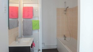 A bathroom with a sink, mirror, towel rack with multiple towels, and a shower area. - Perle Marine - Dieppe (Dieppe)