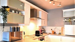 Une cuisine moderne avec des armoires blanches, une cuisinière en acier inoxydable et un four encastré.