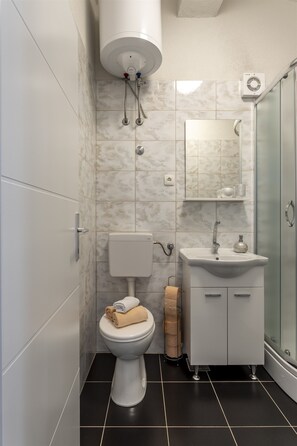 Bañera con ducha, toallas, papel higiénico
