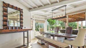 A dining area with a wooden table, bench seating, and a large mirror. - Luxury Palm Desert Mid-Century Home Private Pool Golf Course (Palm Desert)
