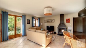 A living room with a sofa, a television, a fireplace, and a dining area with a chair.