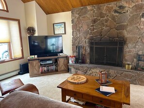 Una sala de estar con chimenea de piedra, un televisor y una mesa de centro de madera.