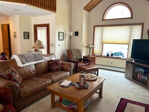 Una sala de estar con un sofá de cuero, una mesa de centro de madera y una televisión.