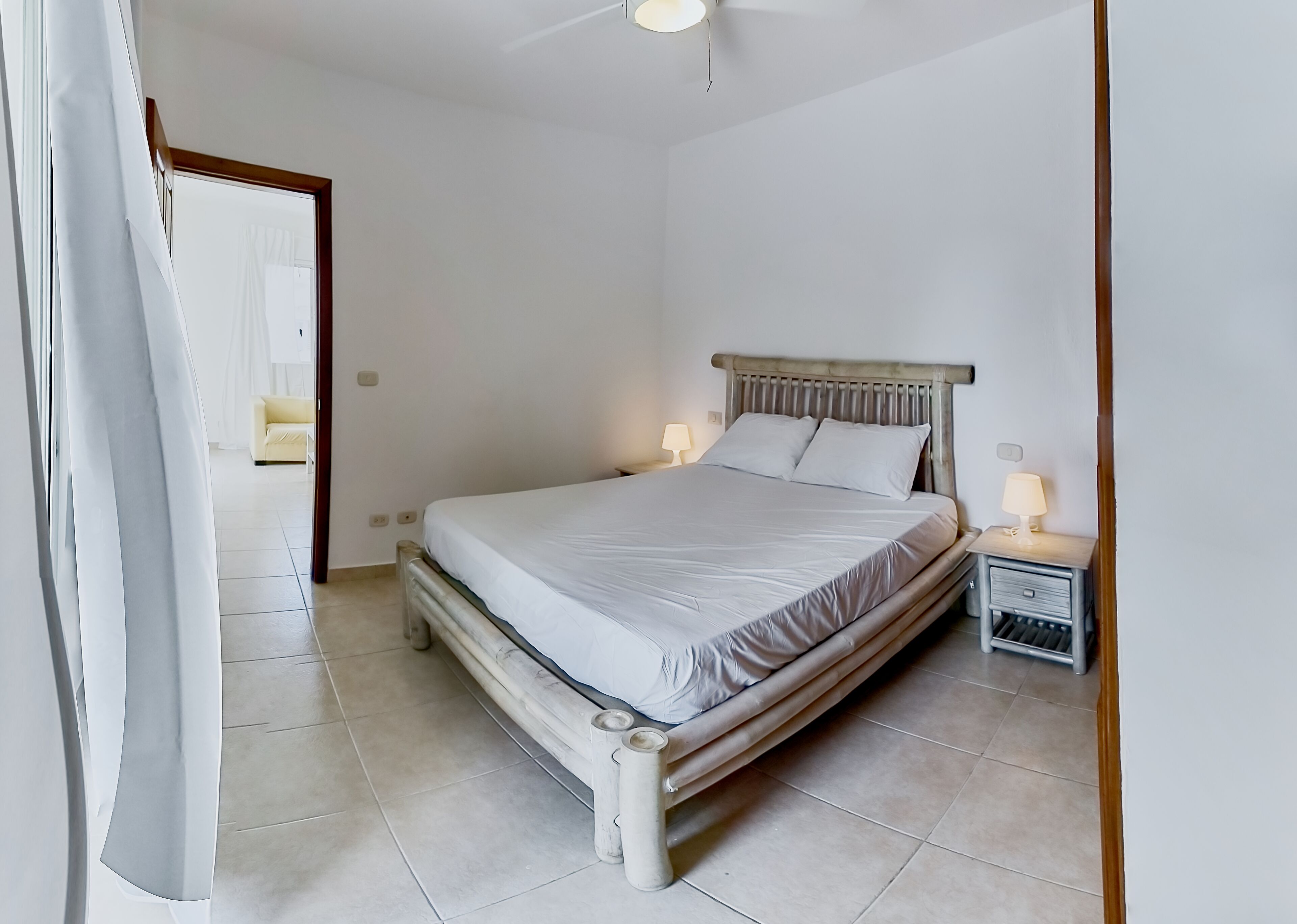 A bedroom with a bed, bedside lamps, and a nightstand.