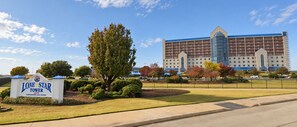 Un hotel con un cartel que indica 3575 unidades, un edificio grande de varios pisos y un césped bien cuidado con un árbol destacado.