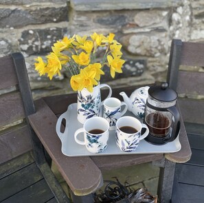 Un plateau avec une théière, deux tasses, un sucrier et un vase avec des fleurs jaunes.