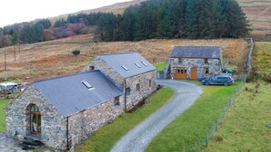 A stone house with a sloped roof and a car parked in front.